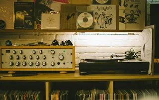 Um pormenor de uma sala com uma móvel com discos de vinil, gira-discos e amplificador