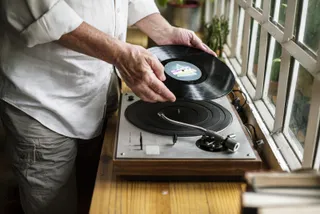 Pessoa colocando um disco de vinil no gira-discos